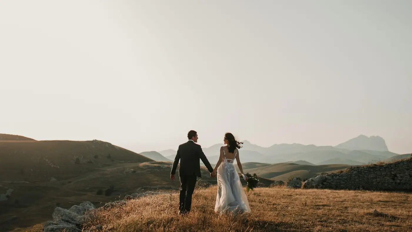 a bride and groom walking on a hill